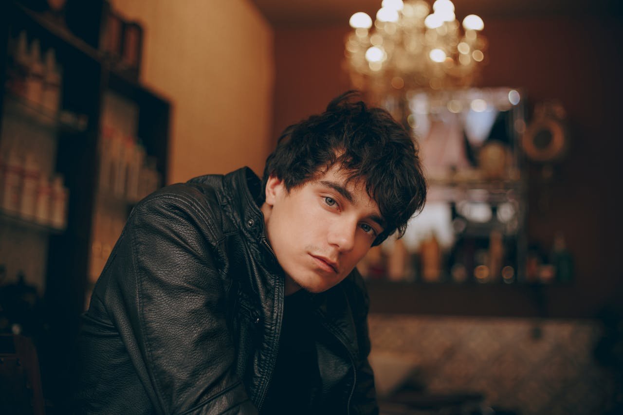 why-choose-us Portrait of a young man in a leather jacket with a blurred background indoors.